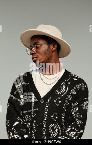 Vertical side view portrait of African American man in style wearing hat against grey background Stock Photo