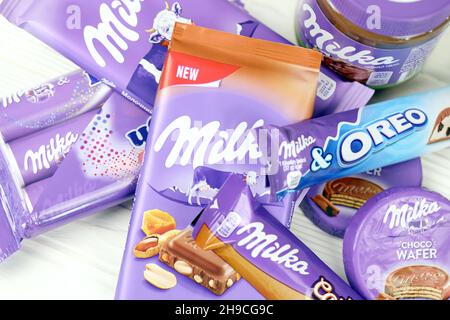 KHARKOV, UKRAINE - JULY 2, 2021: Milka chocolate products with classical lilac color wrapping design on white wooden table Stock Photo