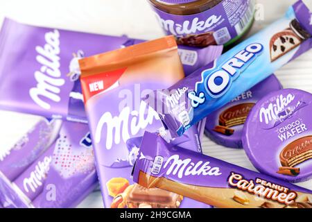 KHARKOV, UKRAINE - JULY 2, 2021: Milka chocolate products with classical lilac color wrapping design on white wooden table Stock Photo