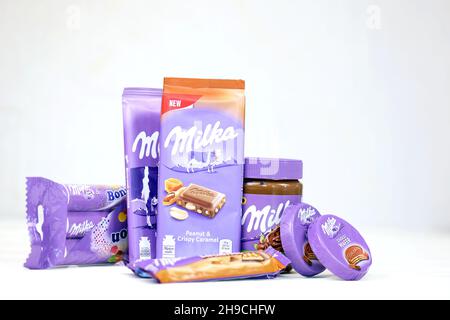 KHARKOV, UKRAINE - JULY 2, 2021: Milka chocolate products with classical lilac color wrapping design on white wooden table Stock Photo