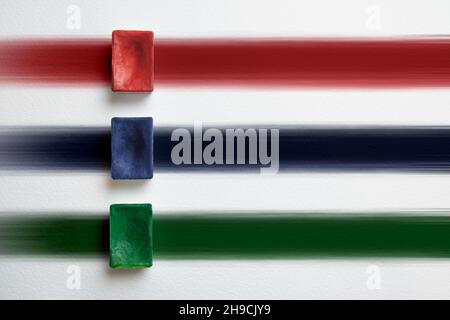 Red, blue and green container of watercolor paint on a background of multicolored stripes. Stock Photo