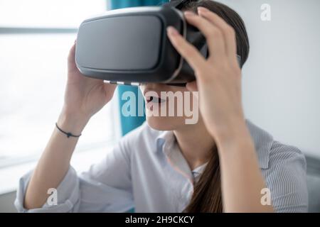 Open-mouthed young woman playing a 3D game Stock Photo