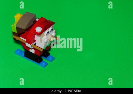 Advent Feast festive Christmas toy decoration with Santa Claus figure. Seasonal colorful composition made with LEGO bricks, against green background. Stock Photo