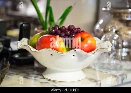 Vase with fruit apples, grapes in the interior Stock Photo