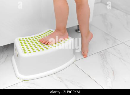 Small feet stand on a baby bathtub stand. Stock Photo