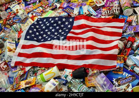 KHARKOV, UKRAINE - AUGUST 10, 2021: US flag on big pile of various wrappings and empty disposable packages and cups from famous branded food and drink Stock Photo