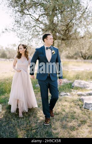 Bride and groom holding hands while walking in the park Stock Photo