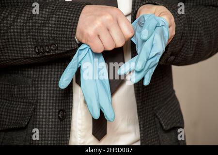 Man puts on protective medical rubber gloves on his hands. Close-up. Stock Photo