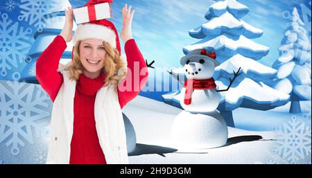 Composition of happy woman in santa hat carrying gift with snowman in background, copy space Stock Photo