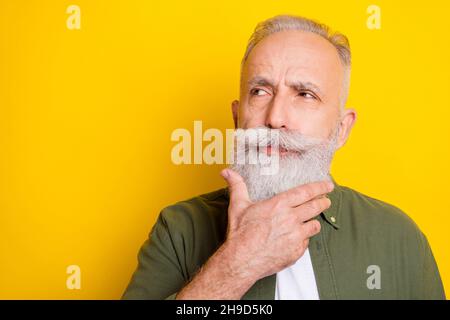 Photo portrait of elder man looking empty space thoughtful isolated vivid yellow color background Stock Photo