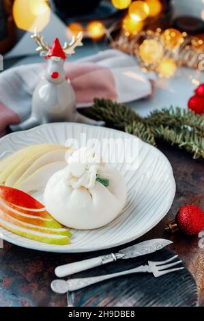 Buffalo Burrata cheese with pear. Traditional Italian, fresh, soft white cheese burrata ball of mozzarella and cream on a round light plate with Stock Photo