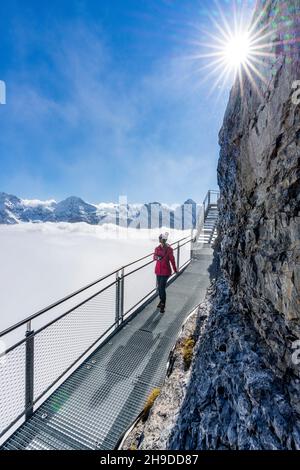 Woman admiring Jungfrau mountain in the fog from the Thrill Walk panoramic walkway, Murren Birg, Bern, Switzerland Stock Photo