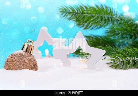 Two white star lanterns and Christmas tree toy on the snow with fir branches. On blue background, snowflakes and bokeh. New year, winter. Copy space Stock Photo
