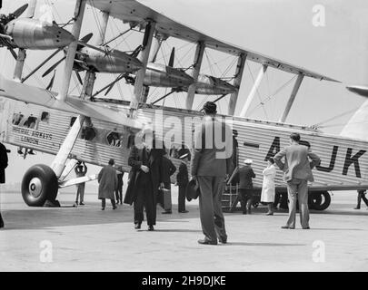 A vintage black and white photograph taken in 1938, showing a Short L.17 Syrinx, serial number G-ACJK, of Imperial Airways at Croydon Aerodrome, outside London. Image showing passengers disembarking from the aircraft.