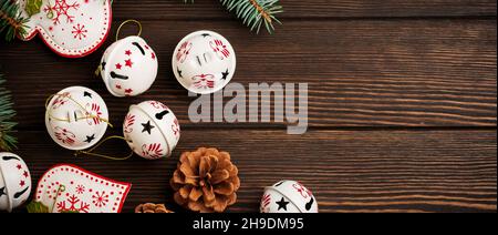 Christmas background with fir branches, toys and bells on wooden old background table. Selective focus. Top view with copy space. Stock Photo