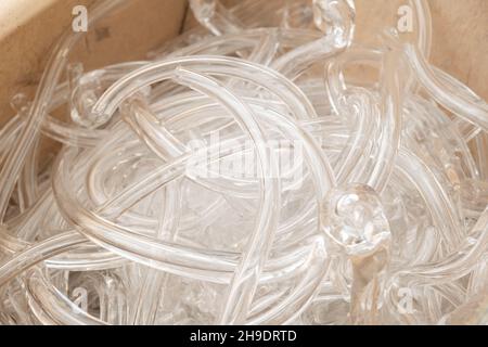 Broken clear glass pipes prepared for recycling and decorative items manufacturing in large wooden crate extreme close view Stock Photo