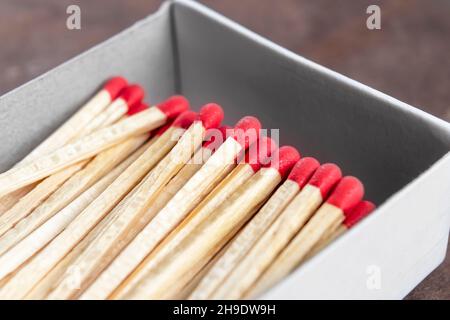 Full open box of matches with red sulfur heads on wooden background. Macro. To light the fire Stock Photo