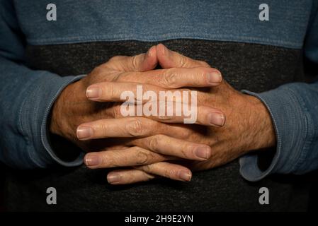 Man with hands clasped together, close up. Stock Photo