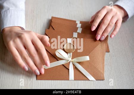woman laid out sealed envelopes on table. invitation envelope with ribbon and wax seal, gift certificate, wedding invitation card Stock Photo