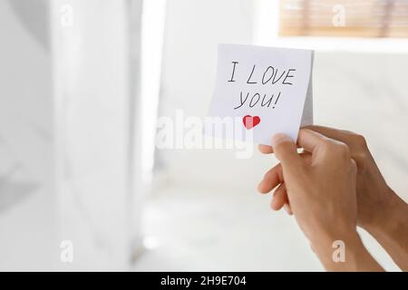 Unrecognizable Woman Putting Sticky Note With I Love You Text On Mirror Stock Photo