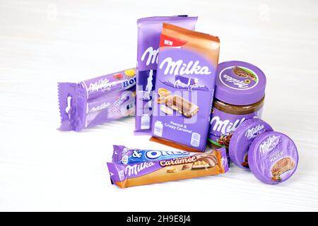 KHARKOV, UKRAINE - JULY 2, 2021: Milka chocolate products with classical lilac color wrapping design on white wooden table Stock Photo