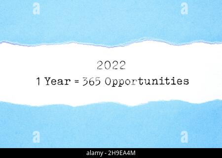 Inspirational message 1 Year 2022 equal to 365 opportunities appearing behind ripped blue paper typed on white sheet. Stock Photo