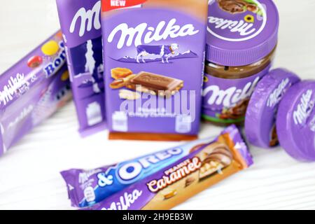 KHARKOV, UKRAINE - JULY 2, 2021: Milka chocolate products with classical lilac color wrapping design on white wooden table Stock Photo