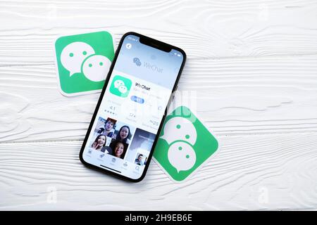 KHARKOV, UKRAINE - MARCH 5, 2021: Wechat messenger icon and application from App store on iPhone 12 pro display screen on white wooden table Stock Photo