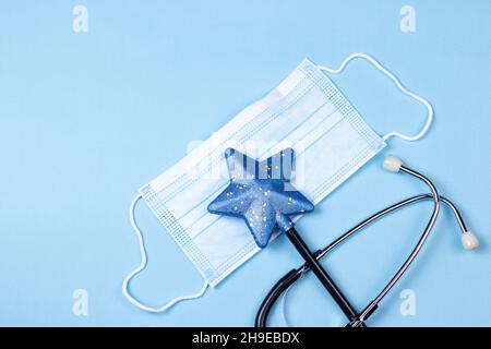 Medical Stethoscope with Santa’s hat and fir tree branch on light background. Christmas, New year's and holiday medical flat lay background. Stock Photo