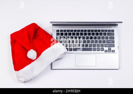 Santa Claus hat and old laptop on white background. Christmas and New Year holydays concept. Stock Photo