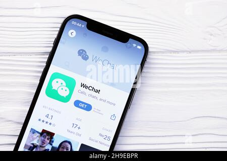 KHARKOV, UKRAINE - MARCH 5, 2021: Wechat messenger icon and application from App store on iPhone 12 pro display screen on white wooden table Stock Photo