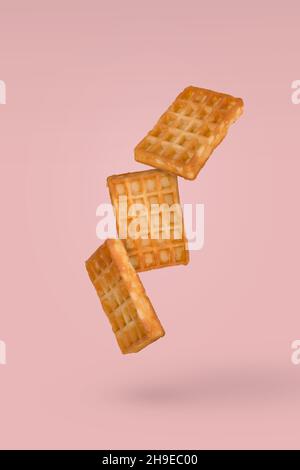 Soft waffles flying in air isolated on a pasel yellow background. Creative food concept. Stock Photo