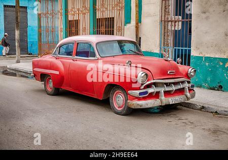 An old classic American car is parked alongside the main street in Regla, a town near Haana in Cuba. Stock Photo