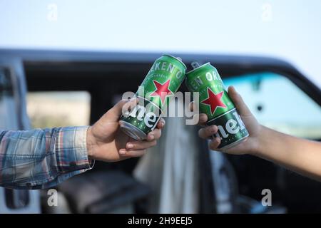 KHARKOV, UKRAINE - JULY 31, 2021: Green tin cans of Heineken pale lager beer in men hands outdoors Stock Photo