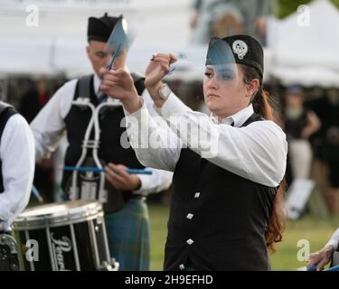 A drummer in a Highland Scottish pipe band flourishes or twirls her drumsticks while playing at a Scottish festival in Utah. Stock Photo