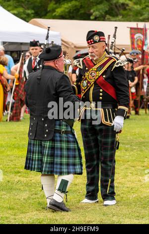 A Highland drum major in full regalia talks to a man in full kilt and tam 'o shanter at a Scottish festival in Utah, USA. Stock Photo