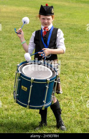 A drummer in a Highland Scottish pipe band flourishes or twirls her drumsticks  at a Scottish festival in Utah. Stock Photo