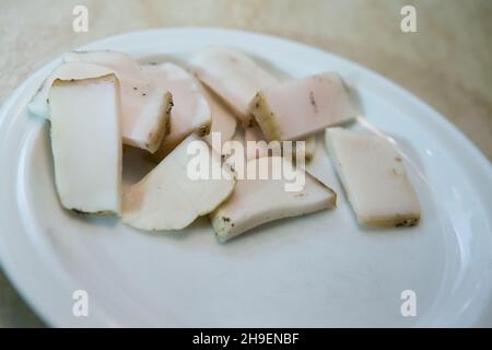 The process of cooking scrambled eggs with lard and sausage. The man prepares two portions. There are pieces of bacon on the plate. Stock Photo