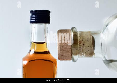 Two bottles with alcohol close up on blurred white background on natural light Stock Photo