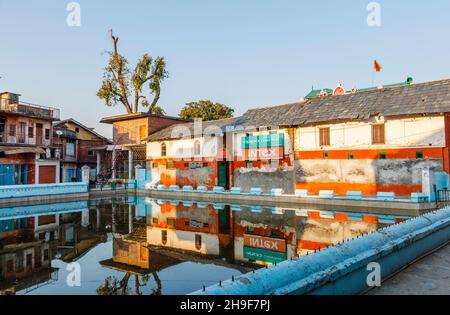 Old buildings reflected in the village tank (pond) in Pragpur, a heritage village in Kagra district, Himachal Pradesh, India Stock Photo