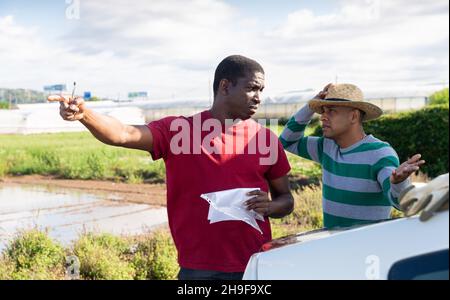 Disgruntled african american farmer reprimanding hispanic contractor Stock Photo