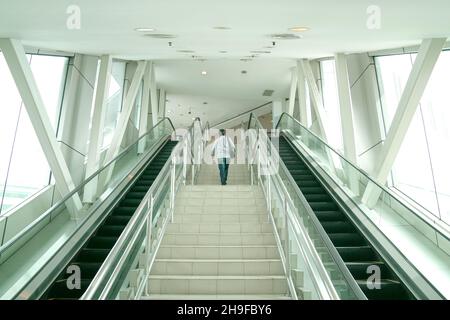 Man going up the stairs inside a modern building. Going back to work or climbing corporate ladder concept. Stock Photo