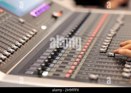 Hand of sound engineer adjusting faders on an audio mixing console. Selective focus. Stock Photo