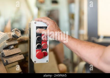 One person pushing a button in a wood factory Stock Photo