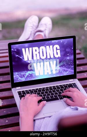Text caption presenting Wrong Way. Business concept taking an unsuitable or undesirable manners or direction Laptop Resting On Lap Of Woman With Cross Stock Photo