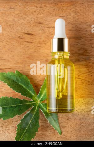 Cannabis leaf Serum, cosmetics, hemp oil. Bottle or vial with a dropper and hemp leaf on wooden board. Natural cosmetics concept. Stock Photo