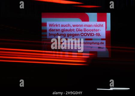 Dresden, Germany. 07th Dec, 2021. Cars drive past an LED wall advertising the booster vaccination against Covid-19 in the morning. Credit: Robert Michael/dpa-Zentralbild/dpa/Alamy Live News Stock Photo