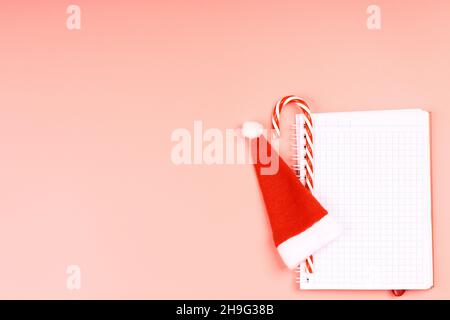 Winter creative layot. Notebook for monitoring Christmas spending on gifts with New Year attributes on a pink background. minimalistic christmas scand Stock Photo
