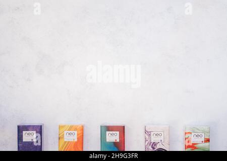 Packs of Neo smoking sticks with different flavors on white concrete surface. Cigarettes for use with Glo heating device. Copy space. Flat lay. Top vi Stock Photo