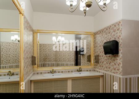 Two modern ceramic washbasins with mirrors in the restroom of the restaurant. Ceramic sink with bronze mixer in contemporary toilet . Interior of Euro Stock Photo
